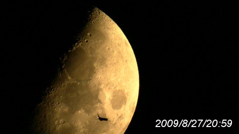 上弦の月を横切る飛行機